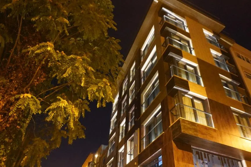 Fragments Hotel binası, akşam aydınlatılmış cephe ve önündeki ağaç dalları