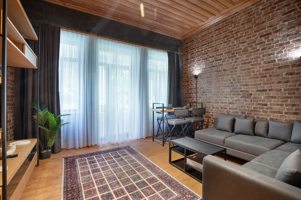 Pırıltı Apartmanı'nda bir daire, tuğla duvar, ahşap tavan ve tül perdeli pencereler